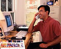 Billede af en mand, der arbejder på computeren, taler i telefon